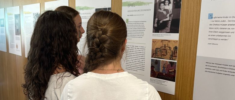Schülerinnen und Schüler betrachten Plakate der Ausstellung.