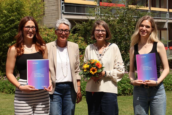 Im Anschluss an die Zeugnisverleihung der Klasse 3BKSP2 überreichte Maria-Elke Schoo-Schemmann (2. von rechts) Maria Berta (rechts und Marie Logusan (links) noch ihre Europässe. Diese bescheinigen ihnen die unterschiedlichen Kompetenzen, die sie erworben haben, als sie die erste Hälfte ihres Anerkennunsjahres über das Programm Erasmus+ in Bilbao beziehungsweise Thessaloniki verbracht haben. Die Leiterin der Fachschulen, Sandra Bandholz (2. von links) bedankte sich bei Maria-Elke Schoo-Schemmann mit einem Blumenstrauß für ihr Engagement und ihre Unterstützung bei der Realisierung des Erasmus+-Programms an den Zinzendorfschulen. 